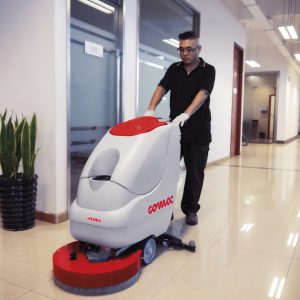 מכונת שטיפה ABILA 20 בשימוש על רצפת משרדים בהירה, אדם דוחף אותה עם כפפות.